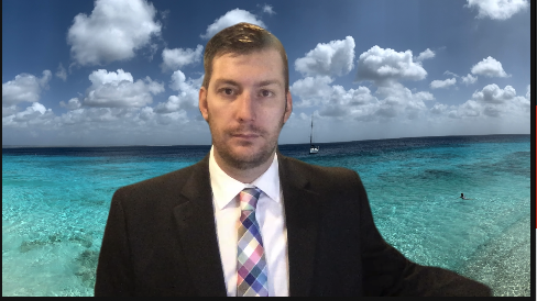 Kevin joining a meeting in a suit and tie with a beachfront Zoom background.