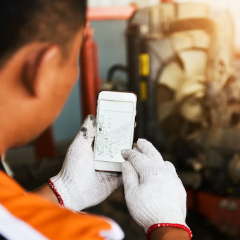 industrial worker looking at schematic plans on his phone in a factory setting